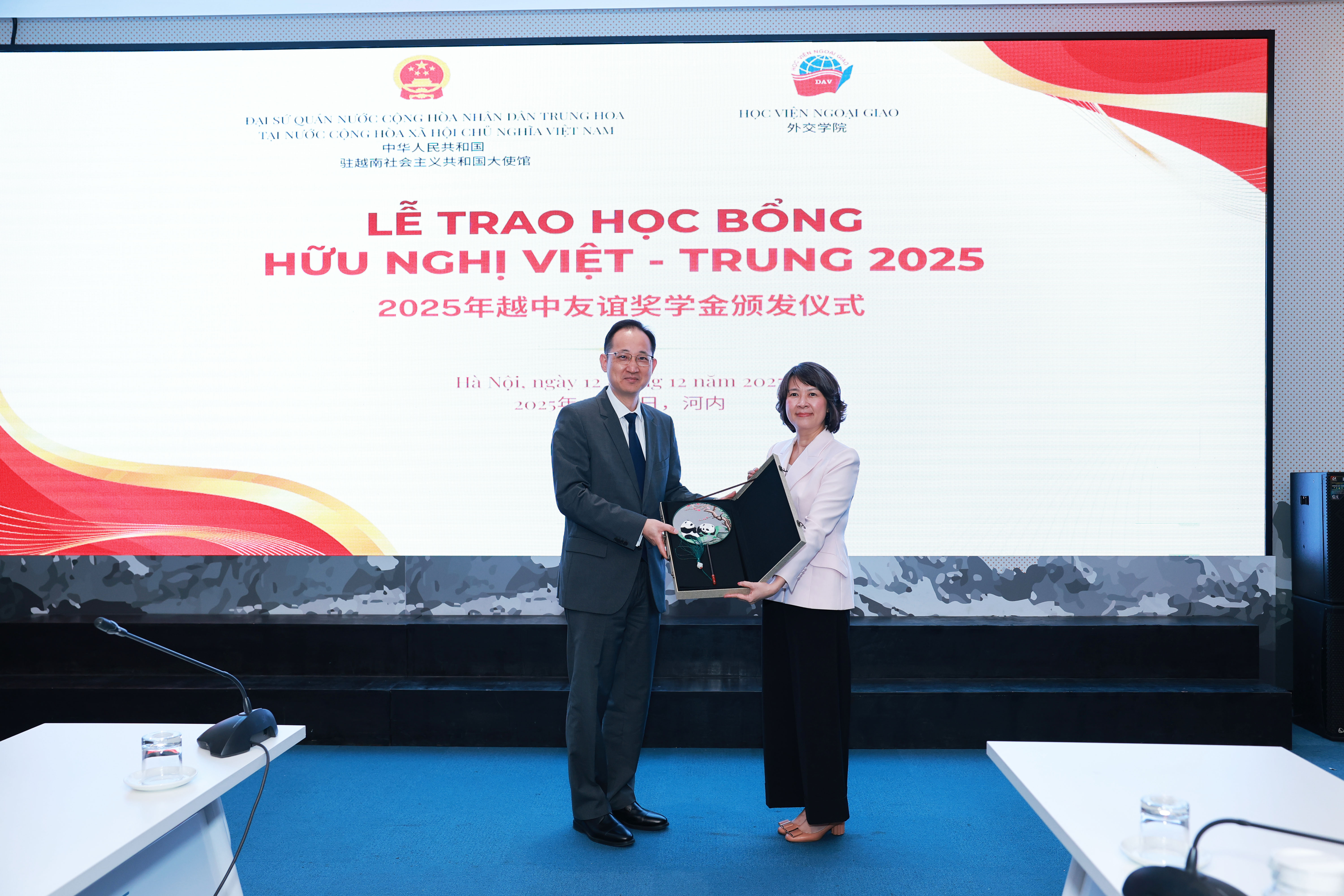 Minister Counsellor Wang Qun receives a commemorative gift from Dr. Nguyen Thi Thin, Vice President of the Diplomatic Academy of Viet Nam